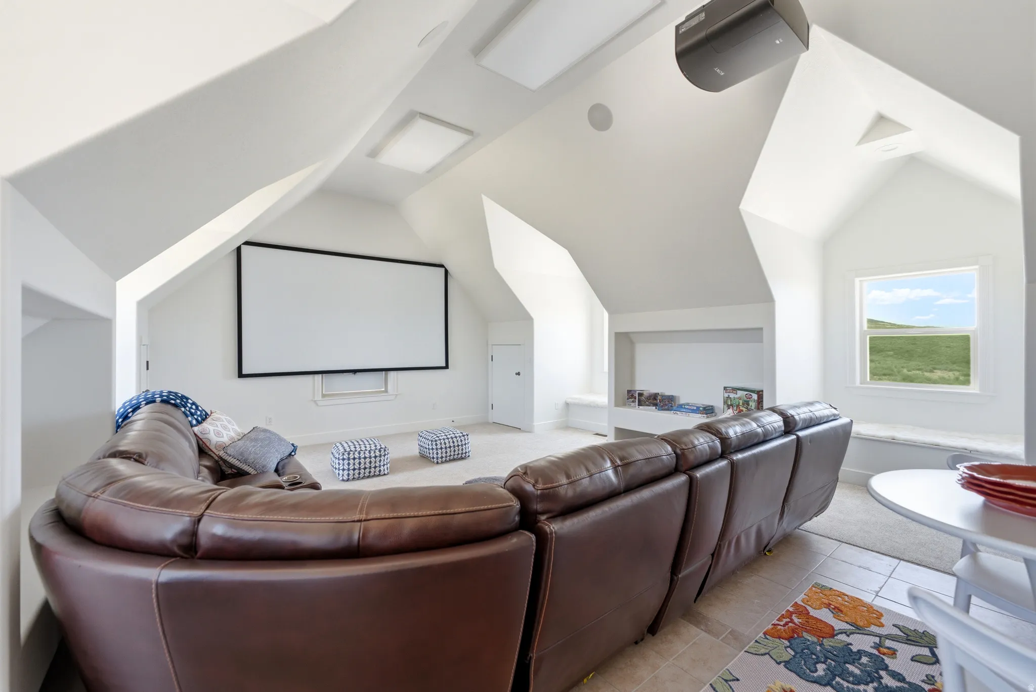 Media room featuring a projector, large screen, built-in window seating, recessed lighting, and a window with outdoor scenery