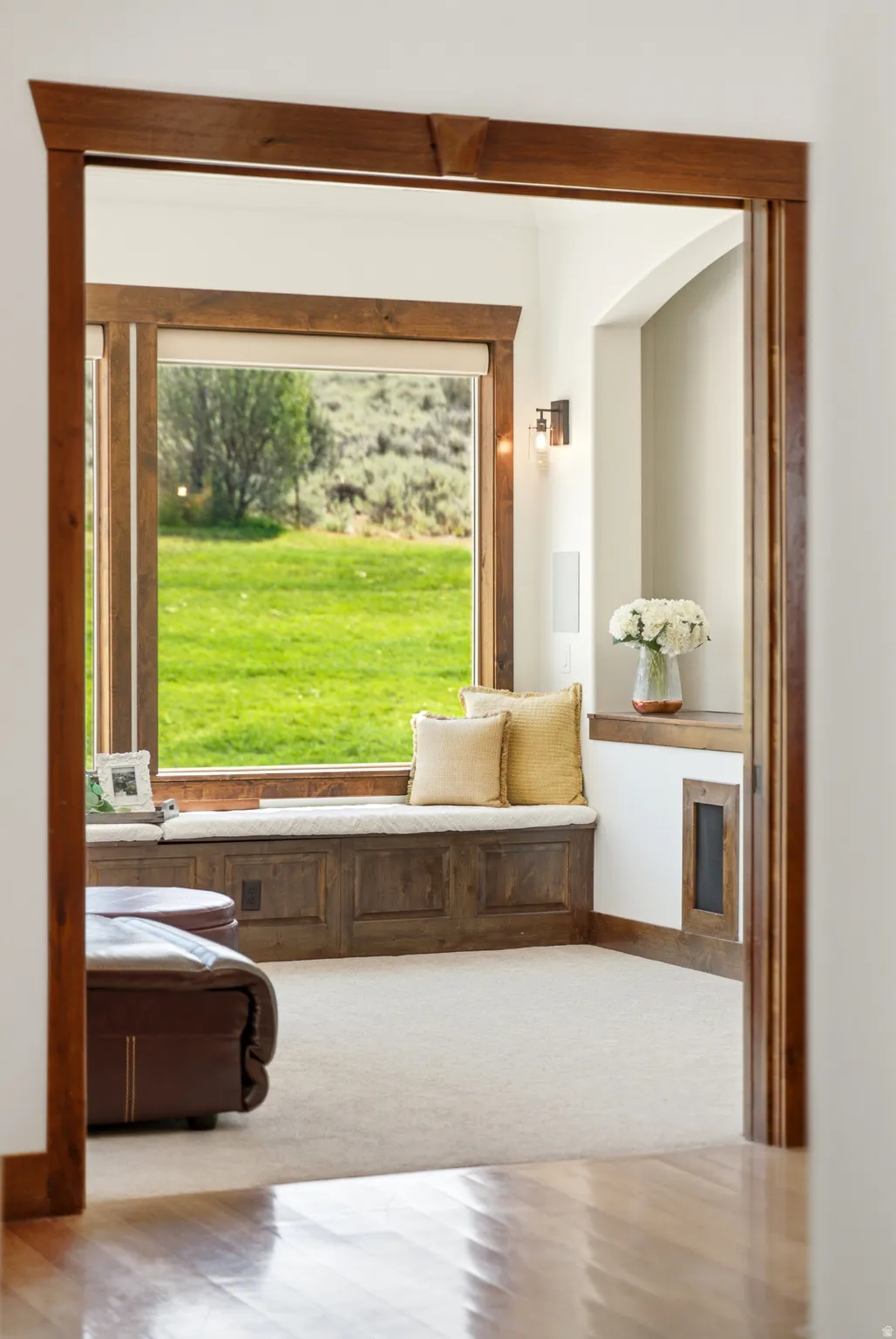 Built-in window seat with storage, framed by dark wood trim, offering expansive outdoor views