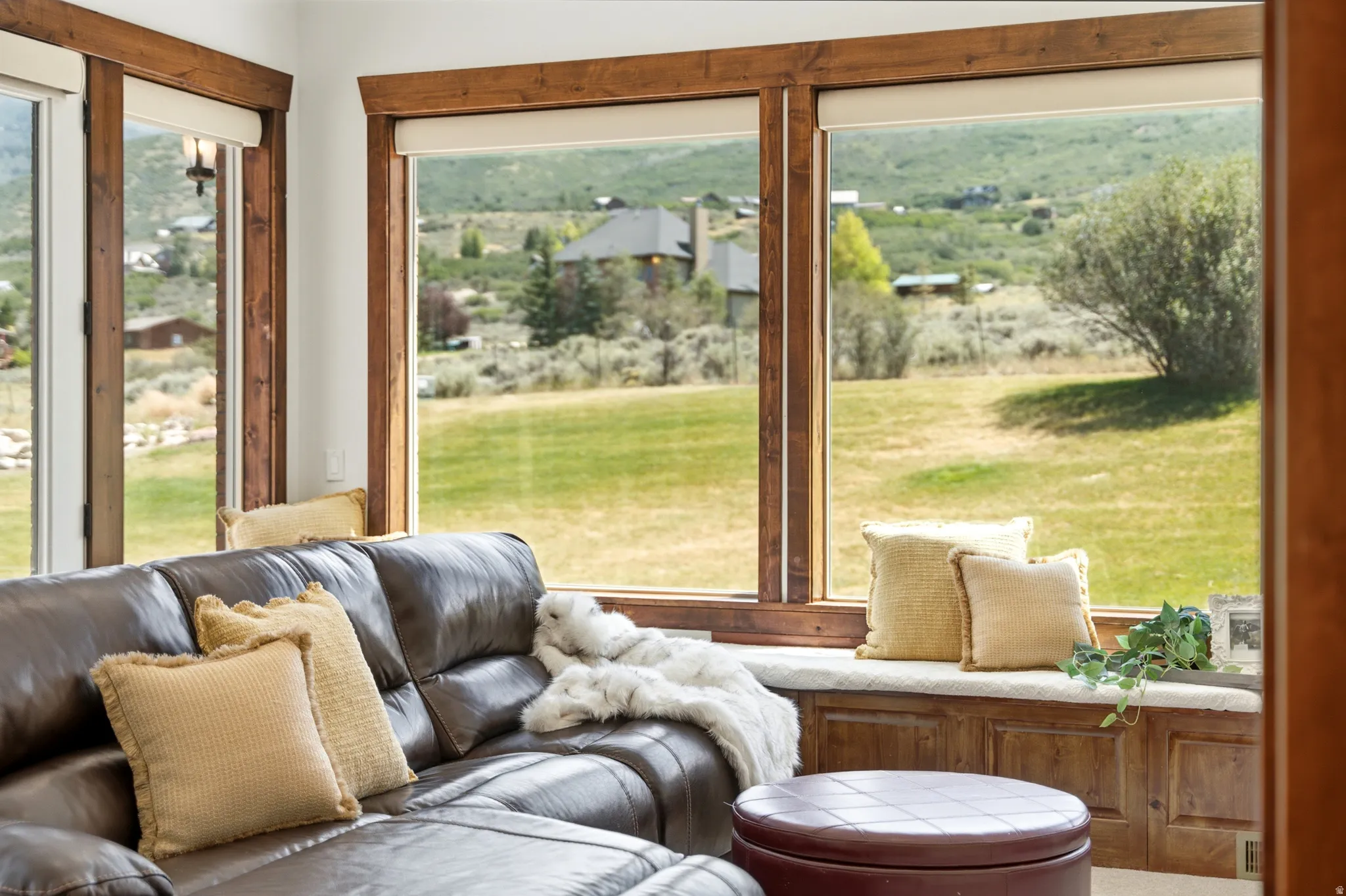Room featuring expansive windows with wood trim, a built-in window seat with storage, and a verdant outdoor landscape