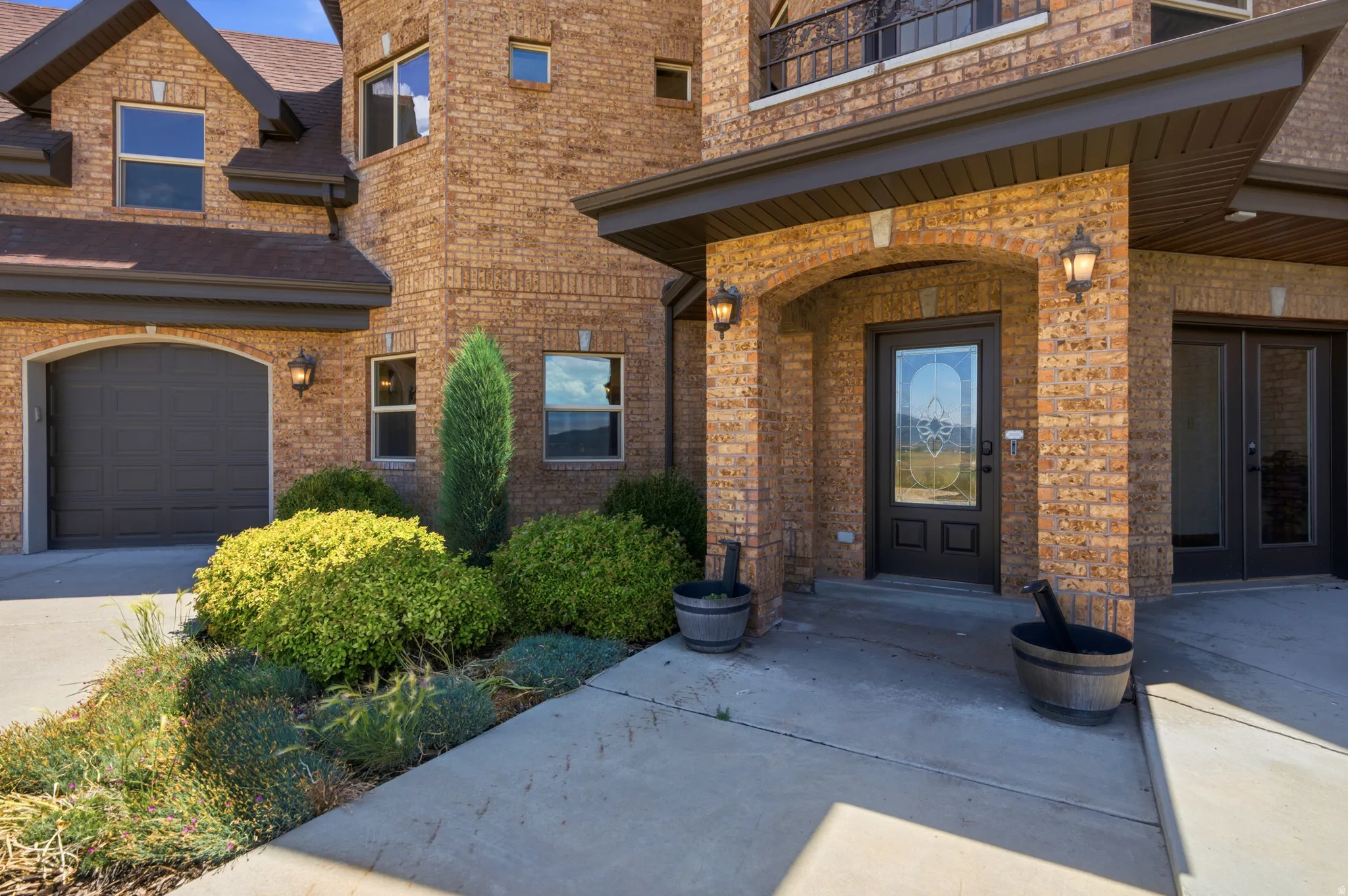 Brick exterior with a prominent arched entry, dark entry door with decorative glass, and dual French doors