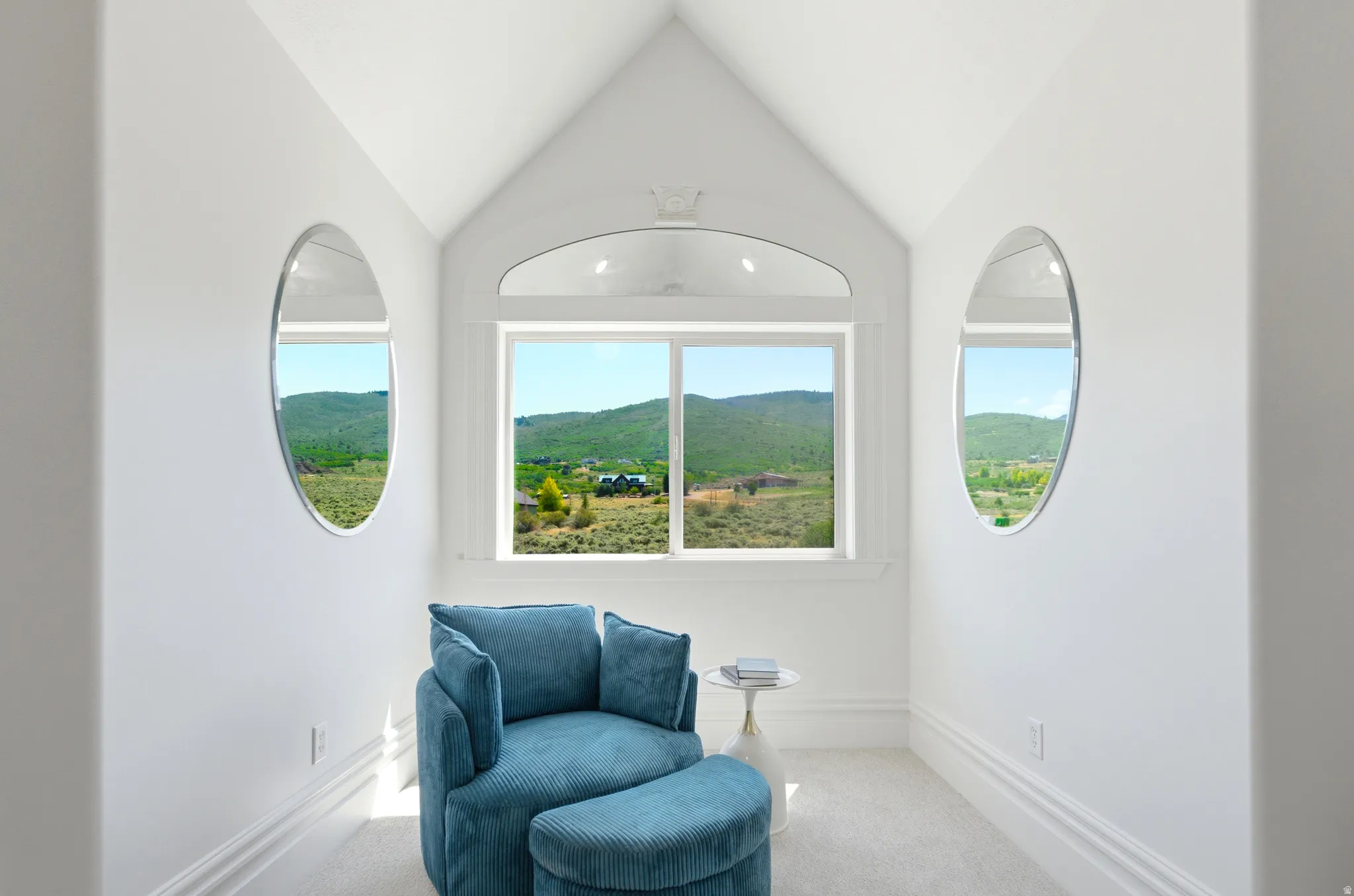 Recessed window alcove featuring a large rectangular window and two oval windows, framed by bright white trim and baseboards