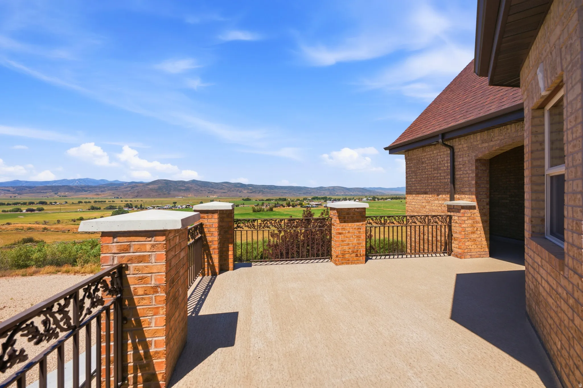 Expansive outdoor patio with decorative metal railing and brick pillars