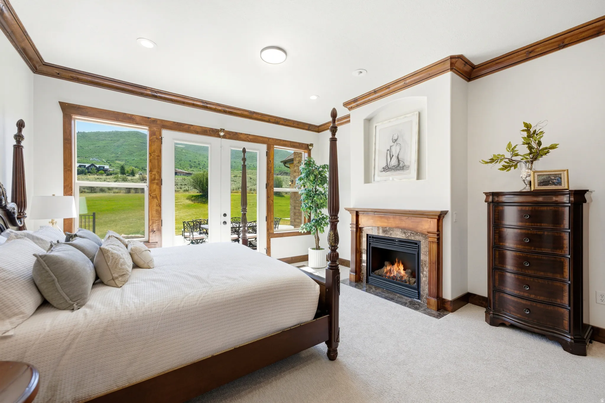 Bedroom featuring a built-in fireplace with a stone surround and wood mantel, large windows, and glass doors opening to the exterior