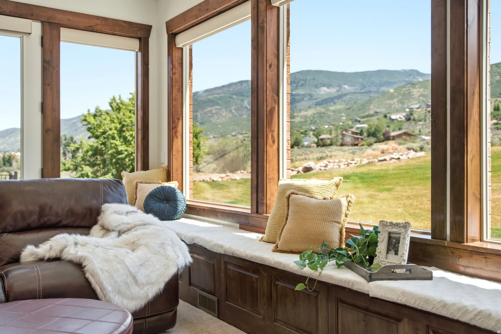 Expansive picture windows with natural wood trim framing a mountain landscape