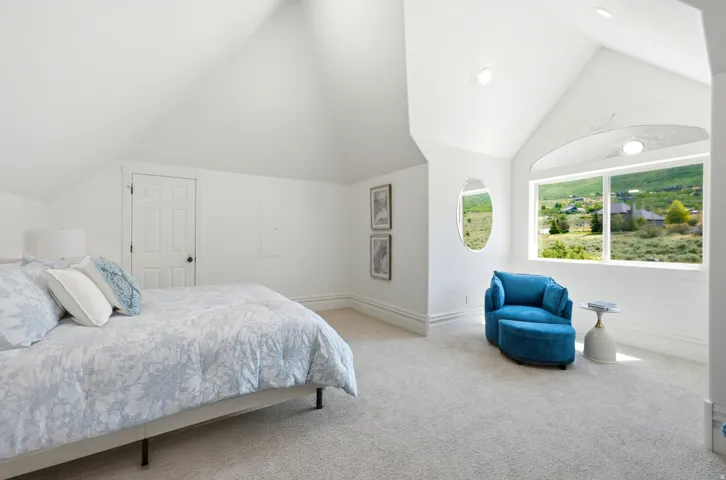 Vaulted white ceilings featuring recessed lighting, a large picture window, and a secondary oval window