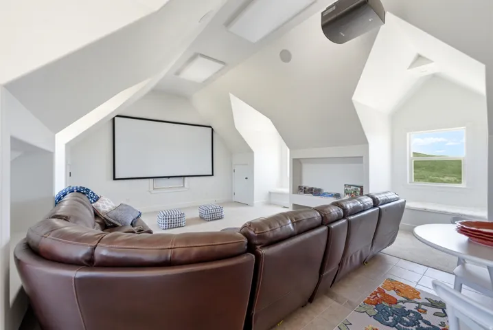 Media room featuring a projector, large screen, built-in window seating, recessed lighting, and a window with outdoor scenery