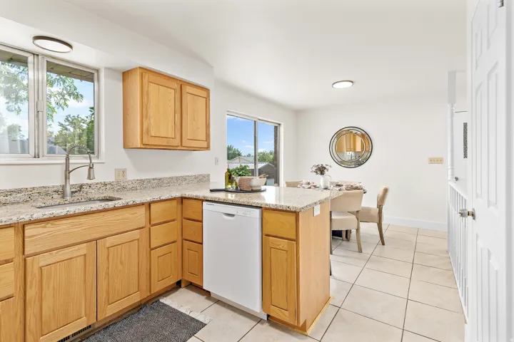 Kitchen featuring light wood cabinetry, granite countertops, and a stainless steel sink with a gooseneck faucet