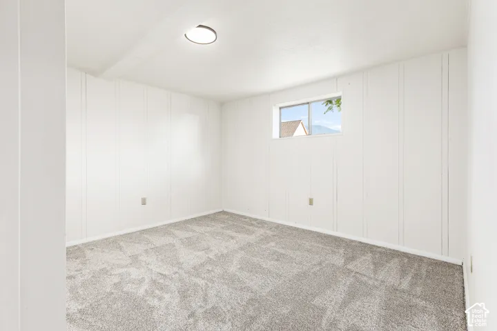 Room featuring white paneled walls, gray patterned carpeting, and a window