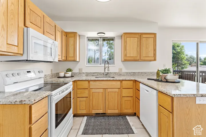 U-shaped kitchen featuring wood cabinetry, granite-finish countertops, white appliances, and a stainless steel sink with a gooseneck faucet