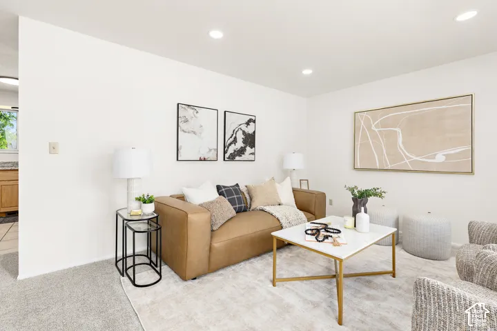 Recessed ceiling lighting illuminates a living space featuring white walls and a neutral color palette