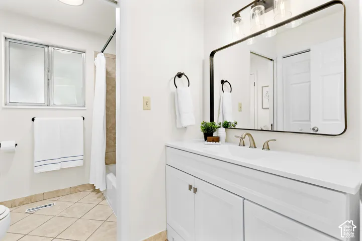 Bathroom featuring a white vanity with an integrated sink, brushed nickel faucet, and a large framed mirror with overhead lighting