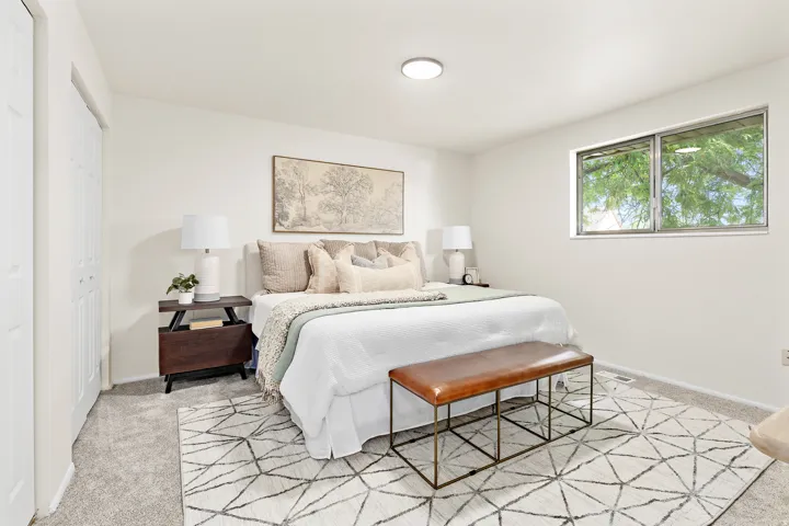 Neutral tone bedroom featuring white walls and light gray carpeting