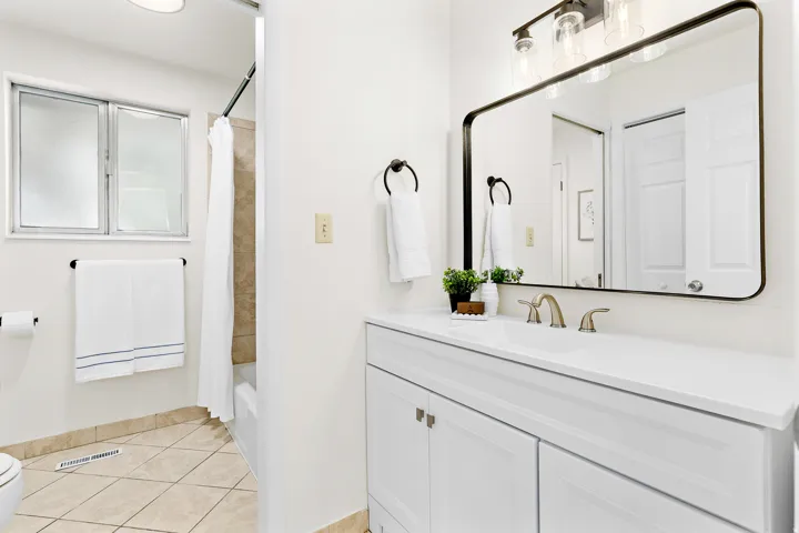 Bathroom featuring a white vanity with an integrated sink, brushed nickel faucet, and a large framed mirror with overhead lighting