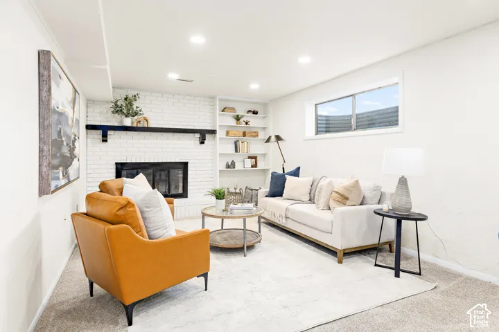 Living area featuring a white painted brick fireplace with a dark wood mantel, built-in shelving, recessed lighting, and a horizontal window