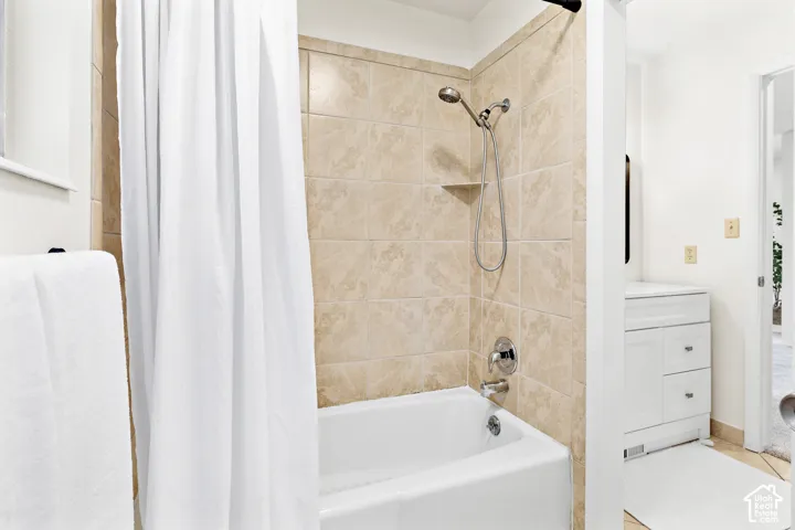 Bathtub with tiled surround featuring a built-in shelf and chrome fixtures
