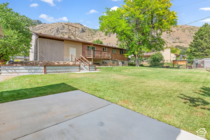 Expansive backyard featuring a manicured lawn, established shade trees, and a concrete patio