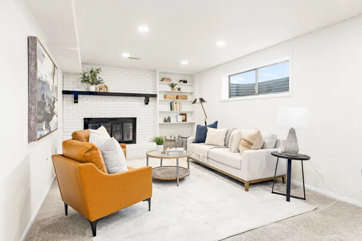 Living area featuring a white painted brick fireplace with a dark wood mantel, built-in shelving, recessed lighting, and a horizontal window