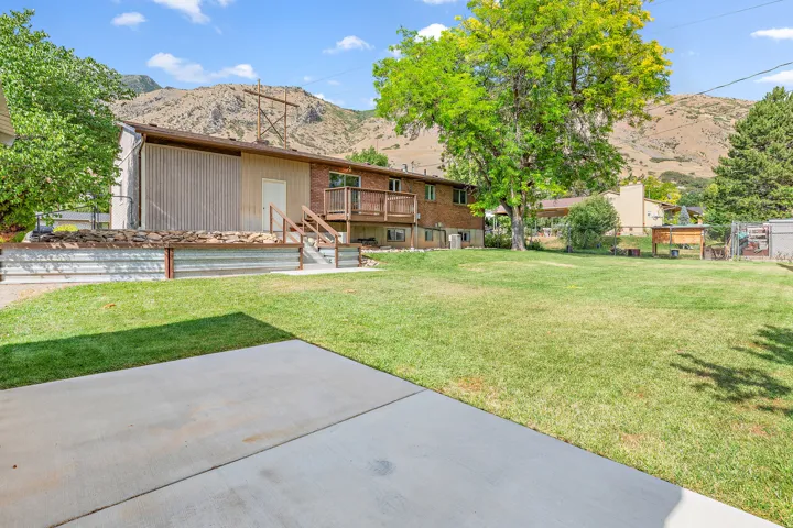 Expansive backyard featuring a manicured lawn, established shade trees, and a concrete patio