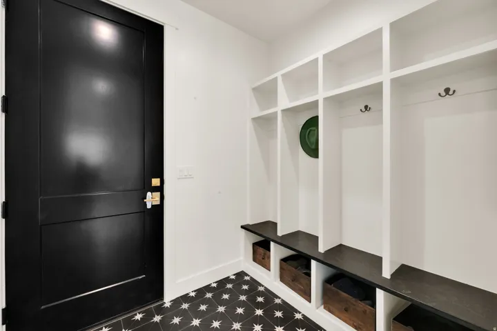 Mudroom featuring built-in storage cubbies, integrated seating, and dark hexagonal star-patterned floor tiles