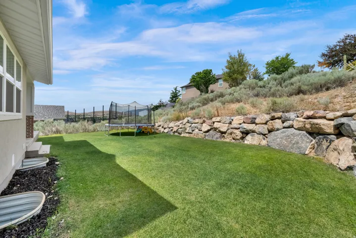 Expansive green lawn with a rock retaining wall and sloped terrain