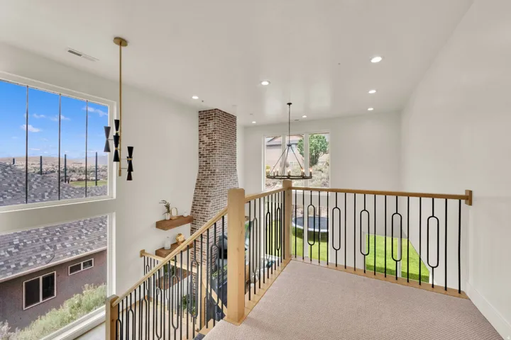 Upper-level landing featuring a contemporary metal and wood-finish railing, recessed lighting, and a modern chandelier