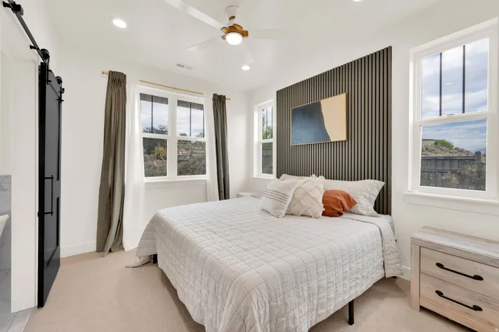 Bright bedroom featuring a dark accent wall, recessed lighting, and a ceiling fan