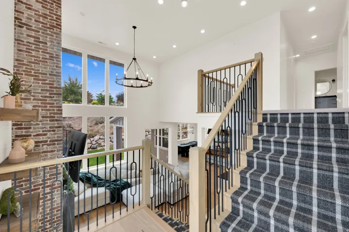 Multi-level interior featuring a contemporary staircase with a plaid runner, light wood-finish railings, and black metal balusters