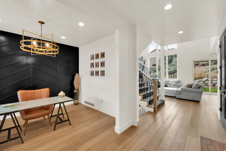 Warm wood-finish flooring extends through an open layout, featuring a prominent black chevron accent wall