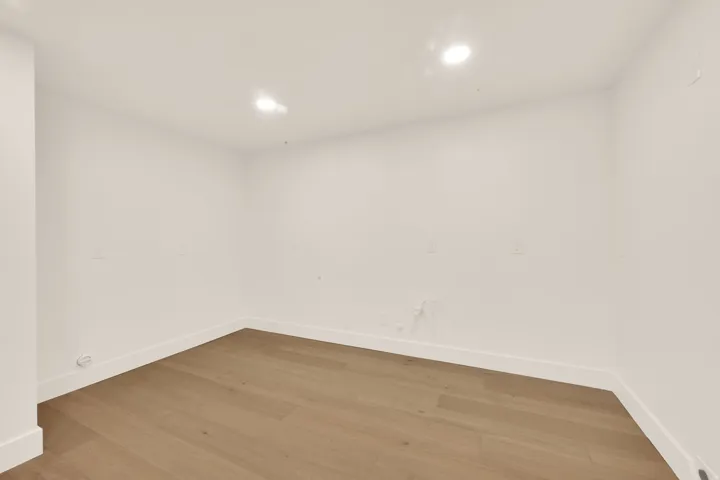 Unfinished kitchen room featuring light wood-finish flooring, recessed lighting, and crisp white walls