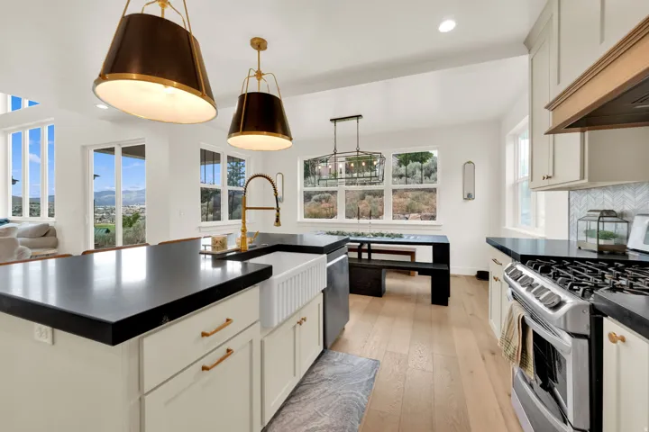 Expansive kitchen island featuring a farmhouse sink, gold-tone faucet, and dark countertops