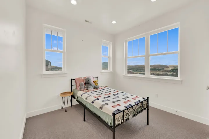 Bright room featuring multiple windows, recessed lighting, white trim, and neutral carpeting