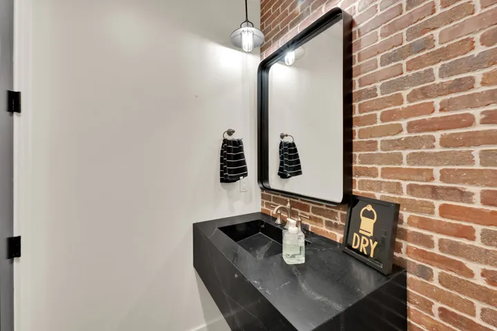 Exposed brick wall accenting a modern vanity with integrated sink
