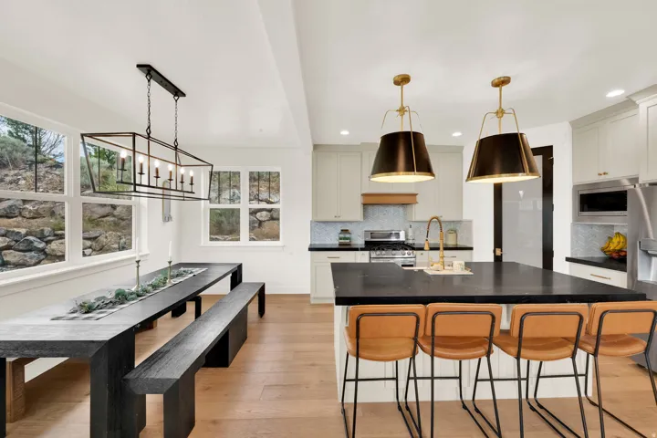 Open-concept kitchen and dining area featuring light wood-finish flooring, white walls, and multiple windows