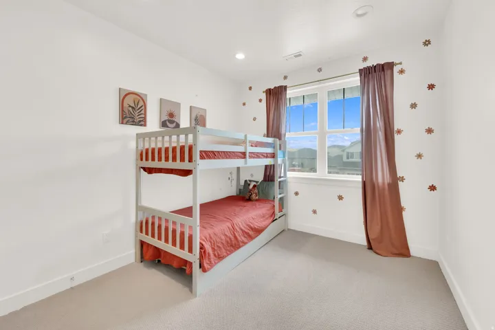 Spacious room with light-colored carpeting, white baseboards, and a large window providing natural illumination