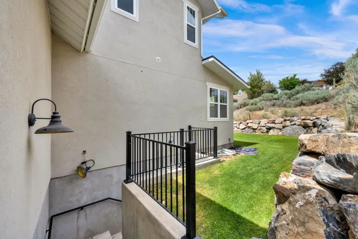 Basement Entrance with exterior stucco finish with white trim windows and a black metal railing