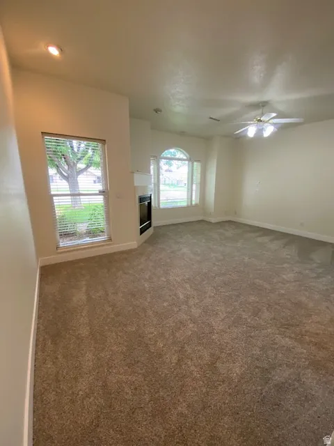 Spacious room with new carpeting, contemporary ceiling fan, recessed lighting, and a corner fireplace with a mantel