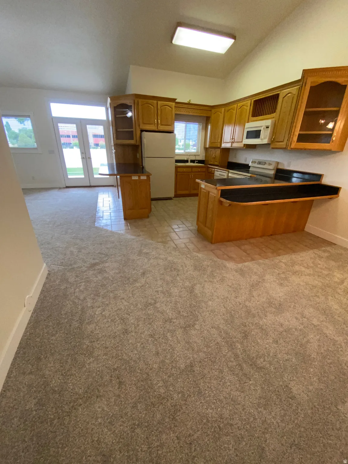 Kitchen with wood-finish cabinetry, solid surface countertops, and tile flooring