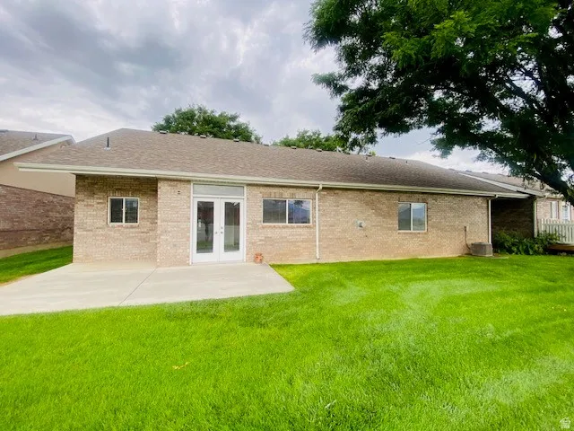 Brick ranch home featuring a spacious front facade with multiple windows, a centered entry door with sidelights, and an attached covered porch