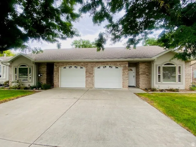 Brick and stucco exterior with arched windows, a two-car garage, and a concrete driveway