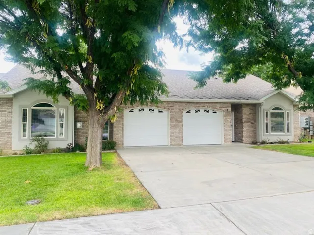 Brick exterior with stucco accents, two bay windows with arched tops, two single-car garages, and a concrete driveway