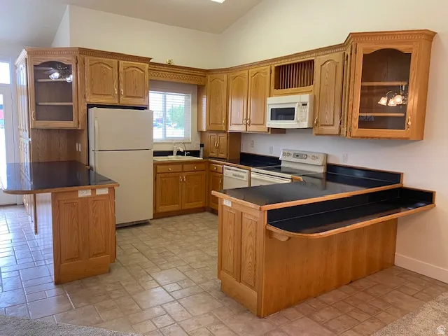 Kitchen featuring wood cabinetry, dark countertops, tiled flooring, and a vaulted ceiling