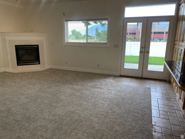 Built-in fireplace with a white mantel, neutral carpeting, glass-paneled French doors, and tiled flooring