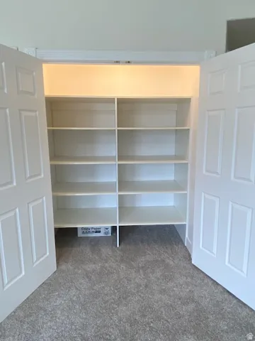 Closet featuring built-in shelving, paneled bifold doors, and overhead lighting