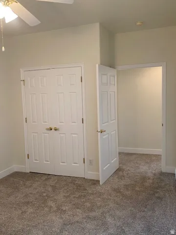 Neutral wall color, carpeted flooring, paneled doors, and ceiling fan