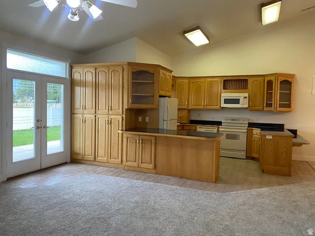 Spacious open-concept kitchen and living area featuring wood-finish cabinetry throughout, stainless steel appliances, a large center island with wood-finish countertop, recessed and ceiling fan lighting, and glass sliding doors opening to the exterior