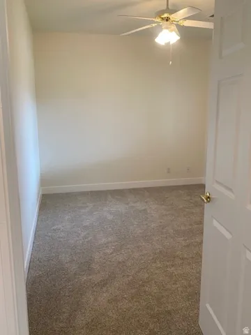 Neutral-toned walls and trim, carpeted flooring, and a ceiling fan with integrated lighting