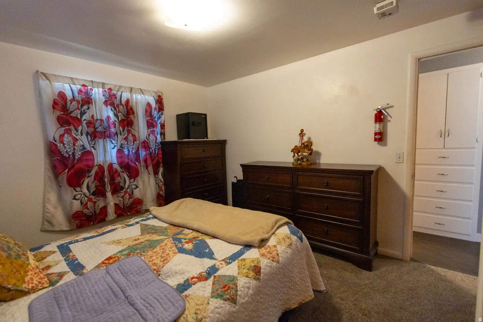 Carpeted bedroom with a window featuring decorative drapes