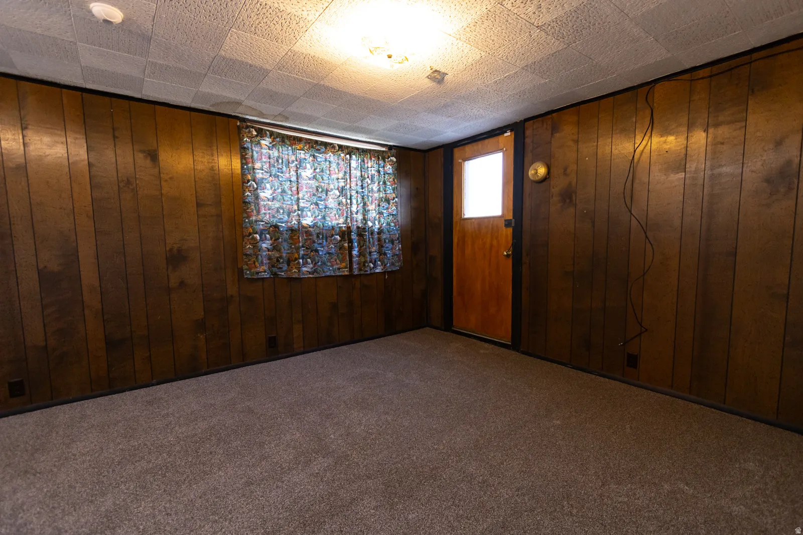 Room featuring wood paneling, textured ceiling, and neutral carpet flooring