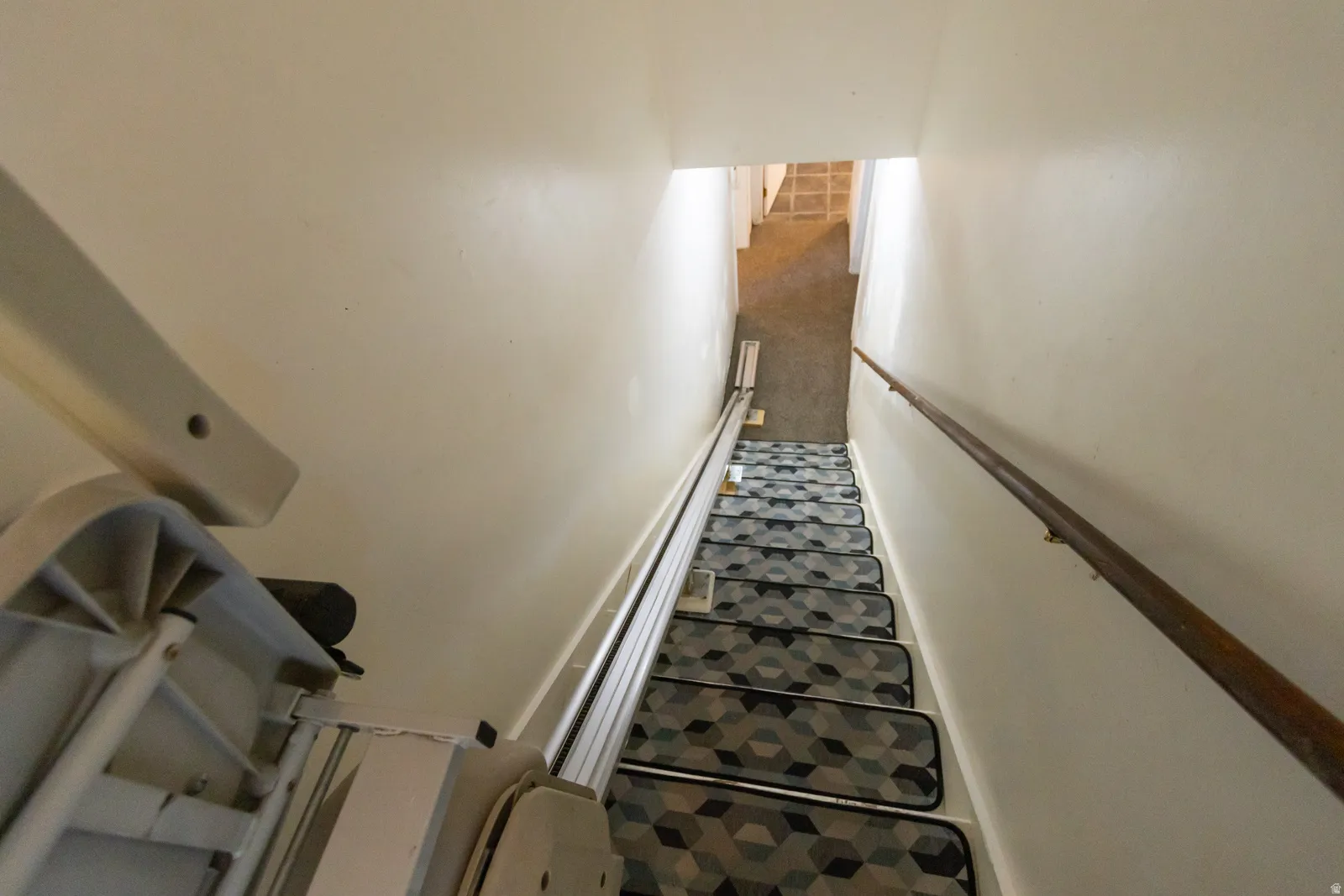Staircase featuring geometric pattern stair treads and a wooden handrail