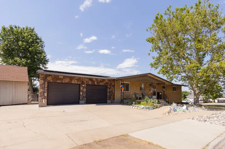 Exterior featuring a two-car garage with stone veneer, an extended concrete driveway, and a covered front entry